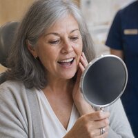 Patient seeing her new smile in a hand mirror